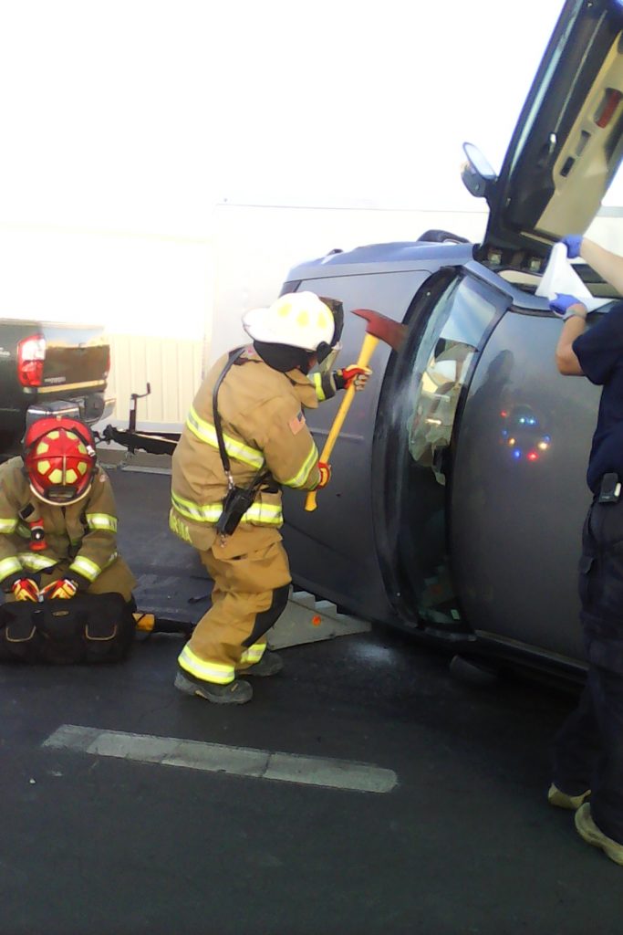 Local Firemen beaking the windshield of the car to gain access to the injured.(picture High Desert Advocate staff)