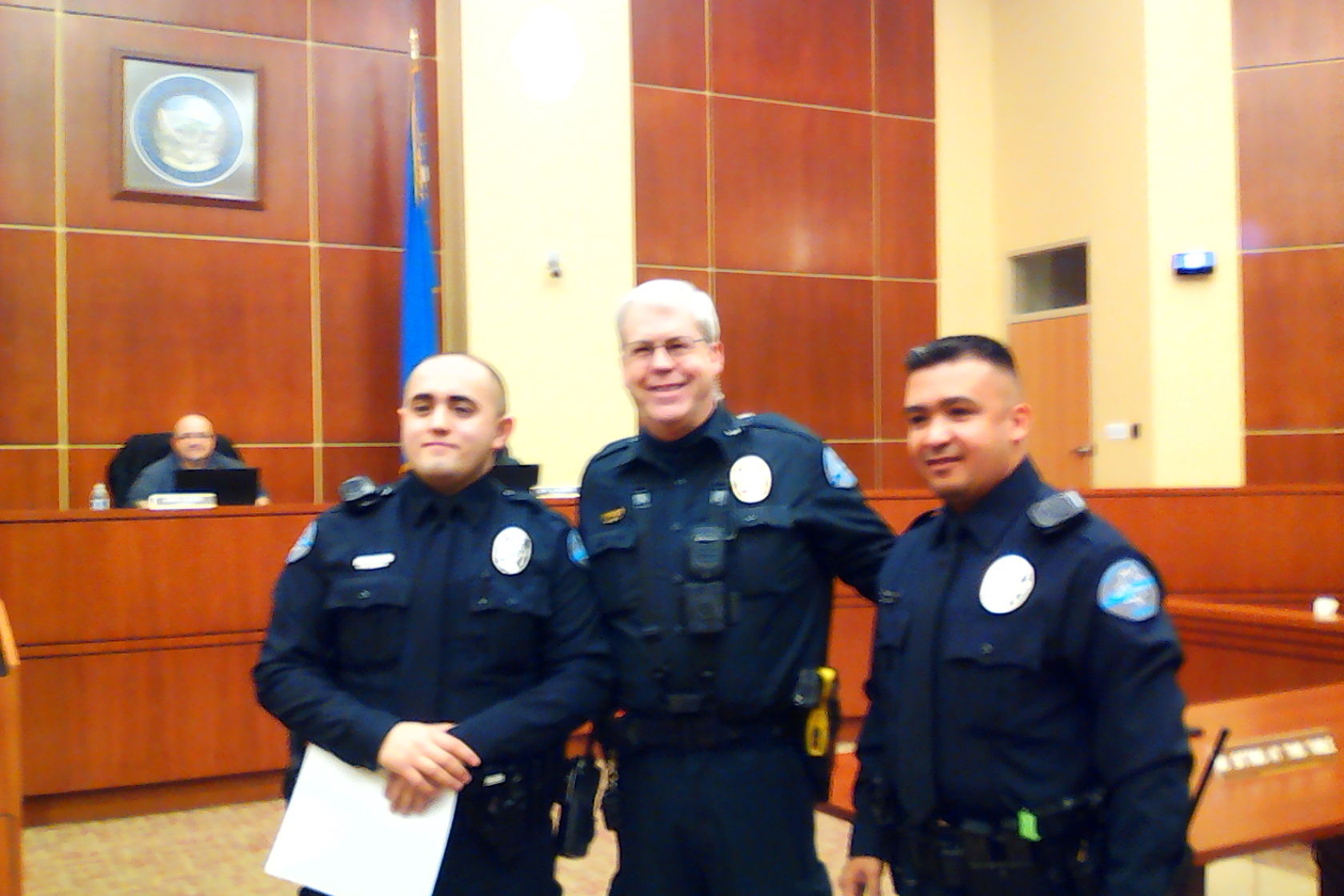 Police Officer Pete Turner receives a recognition plaque for 10 Years of Service from Police Chief Burdel Welsh. Right photo: Fernando Uribe, Police Chief Welsh, and Miguel Pantelakis(Photo High Desert Advocate).